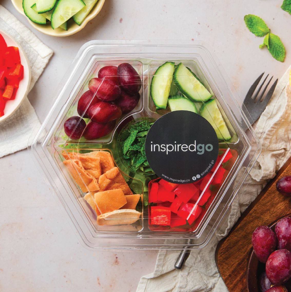 A top-down InspiredGo salad in its patented sealed package, with greens, toppings and dressing kept in separate compartments