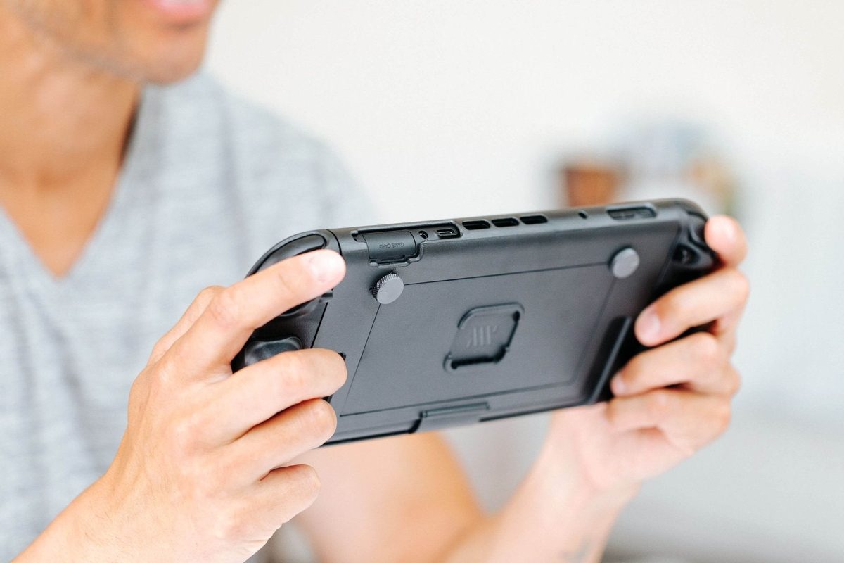Hands holding a Switch 2 in the Basecase, grips wrapped by the fingers