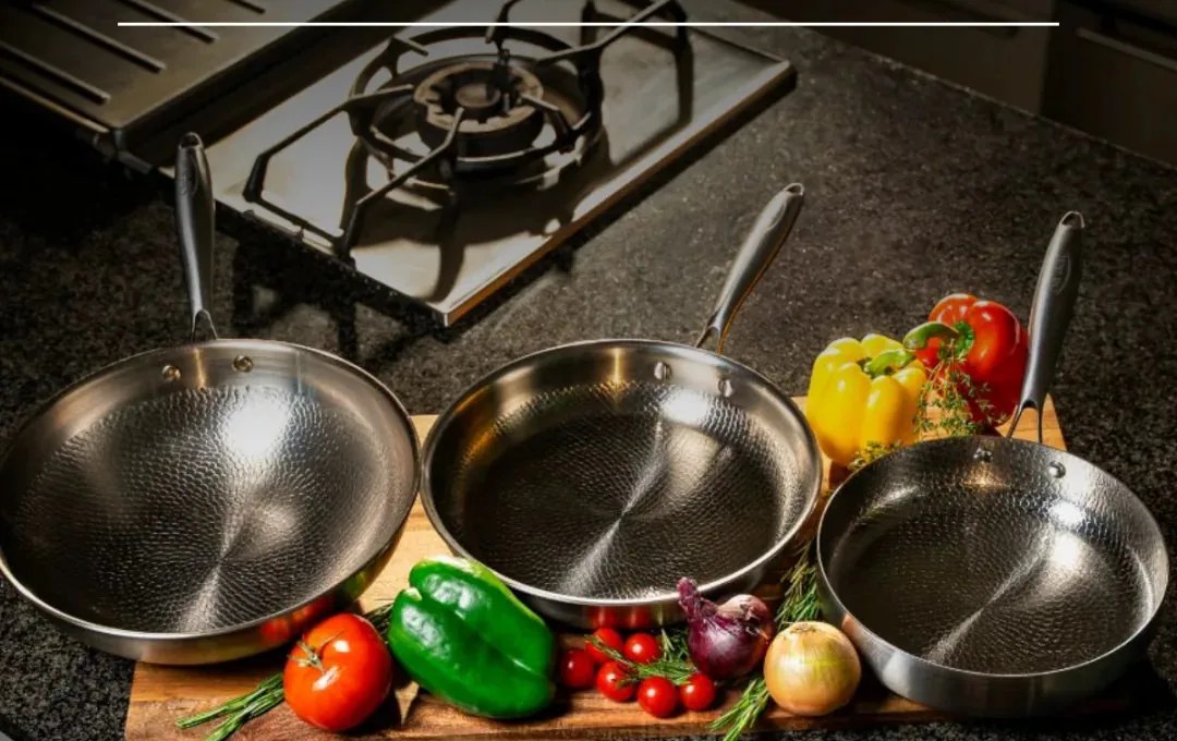 Three Siraat titanium hammered pans on a kitchen counter with fresh vegetables