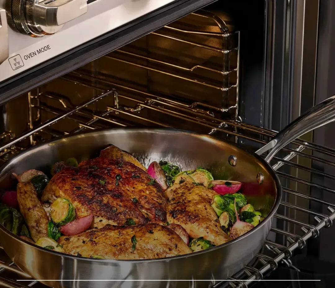 A whole chicken roasting in a Siraat titanium hammered pan inside the oven